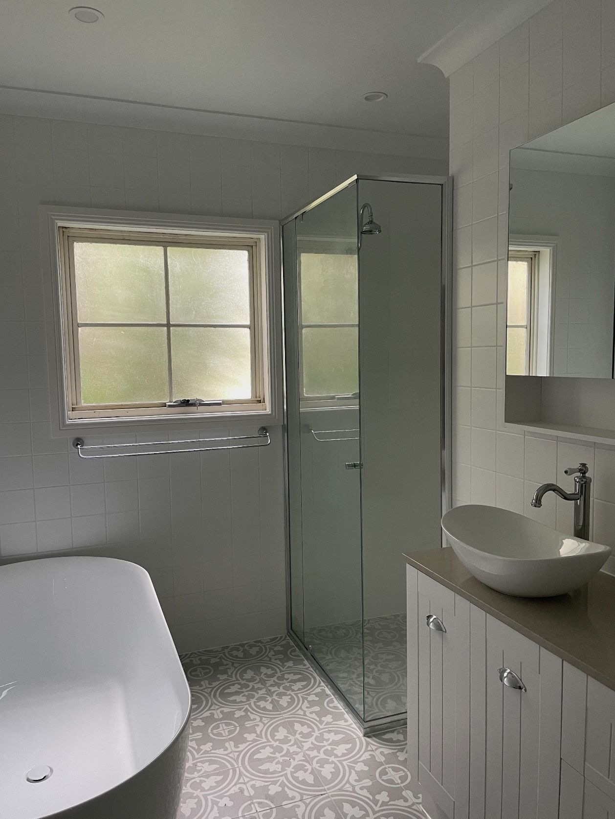 A bathroom with a tub , sink , shower and window.