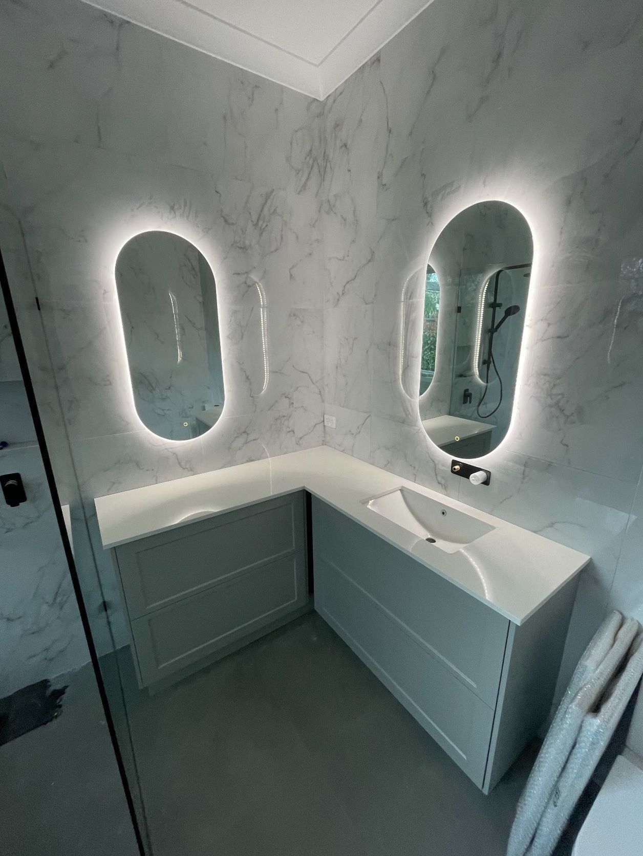 A bathroom with two LED mirrors and a sink.