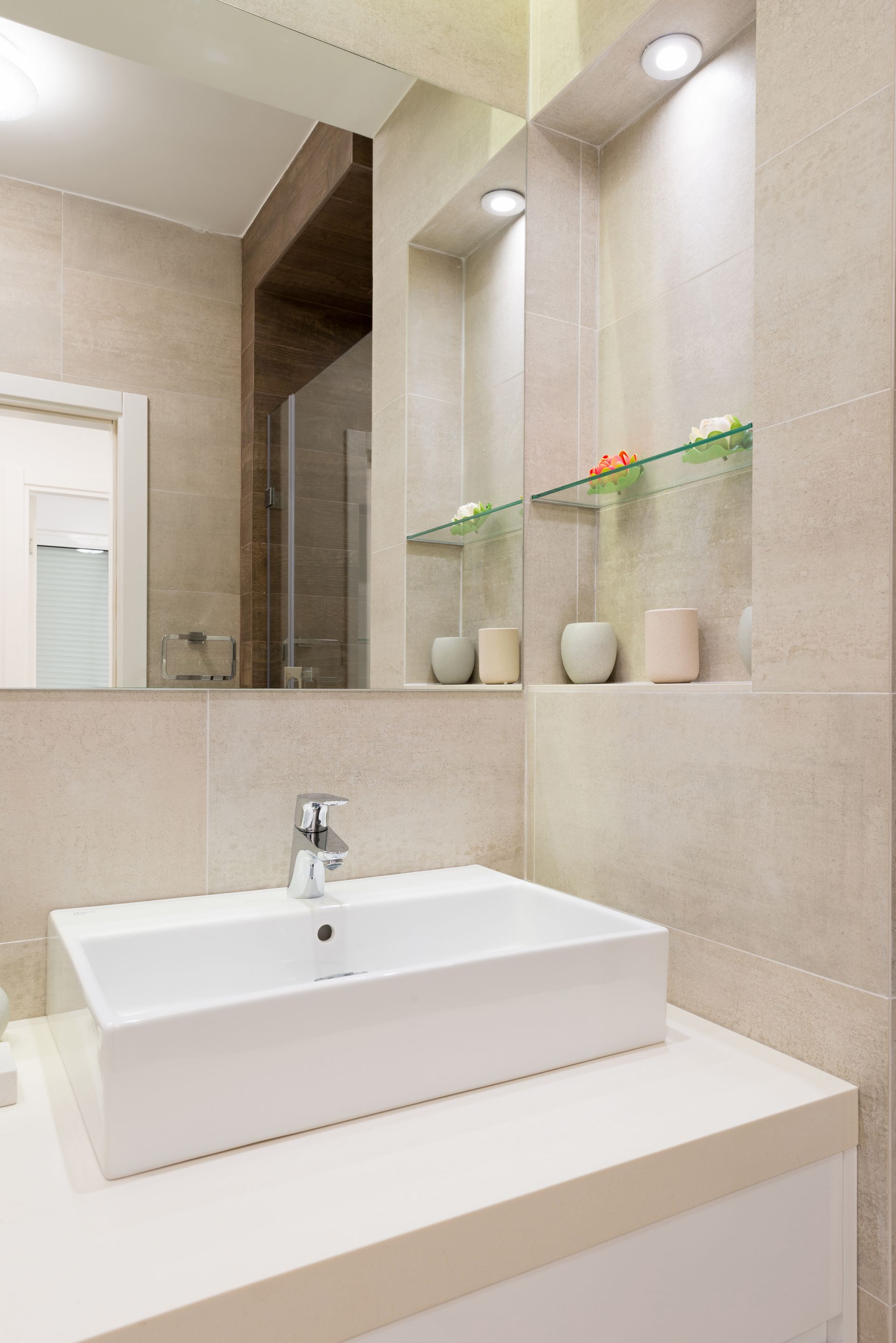 A bathroom with a sink , mirror and shelves.