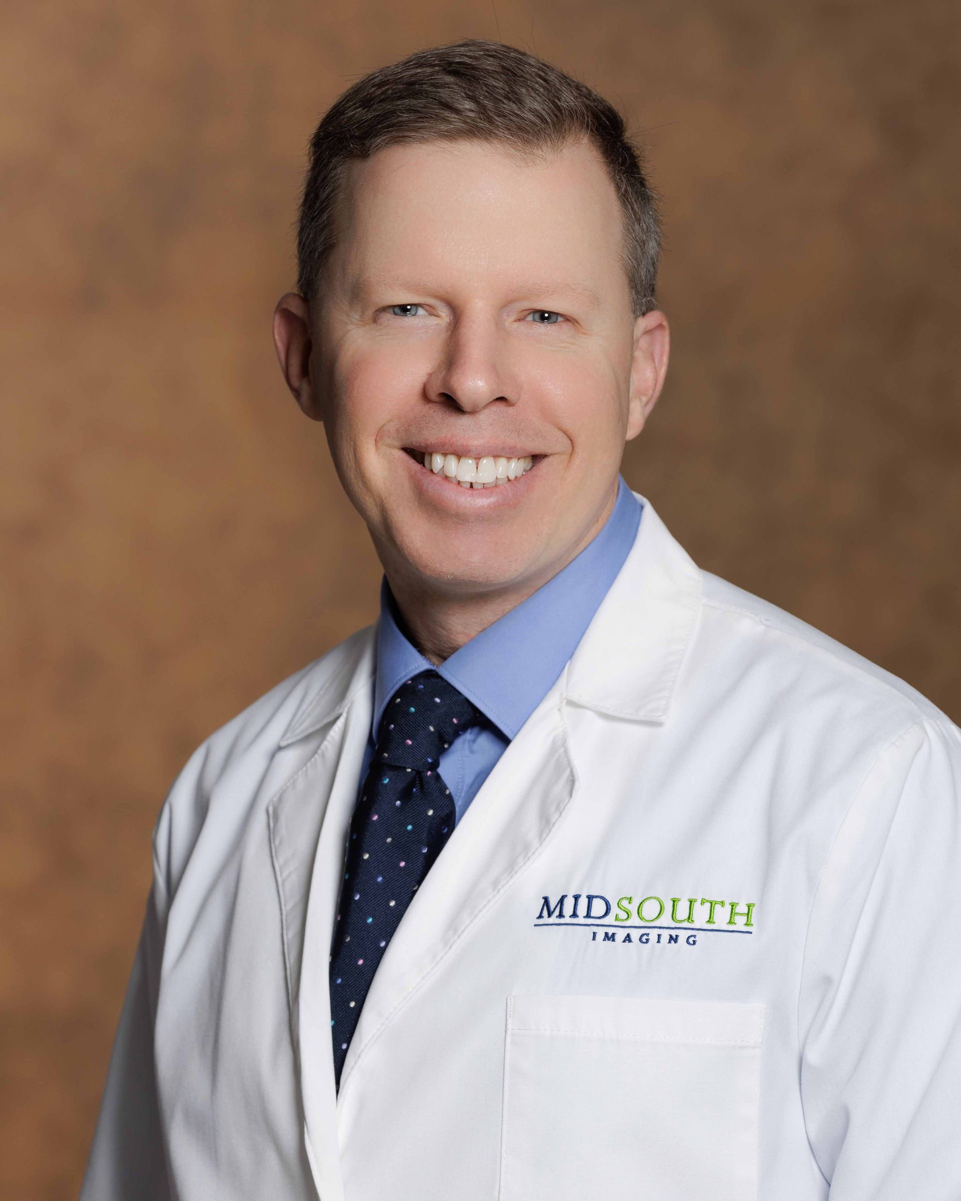 A man wearing a white lab coat with the word midsouth on it