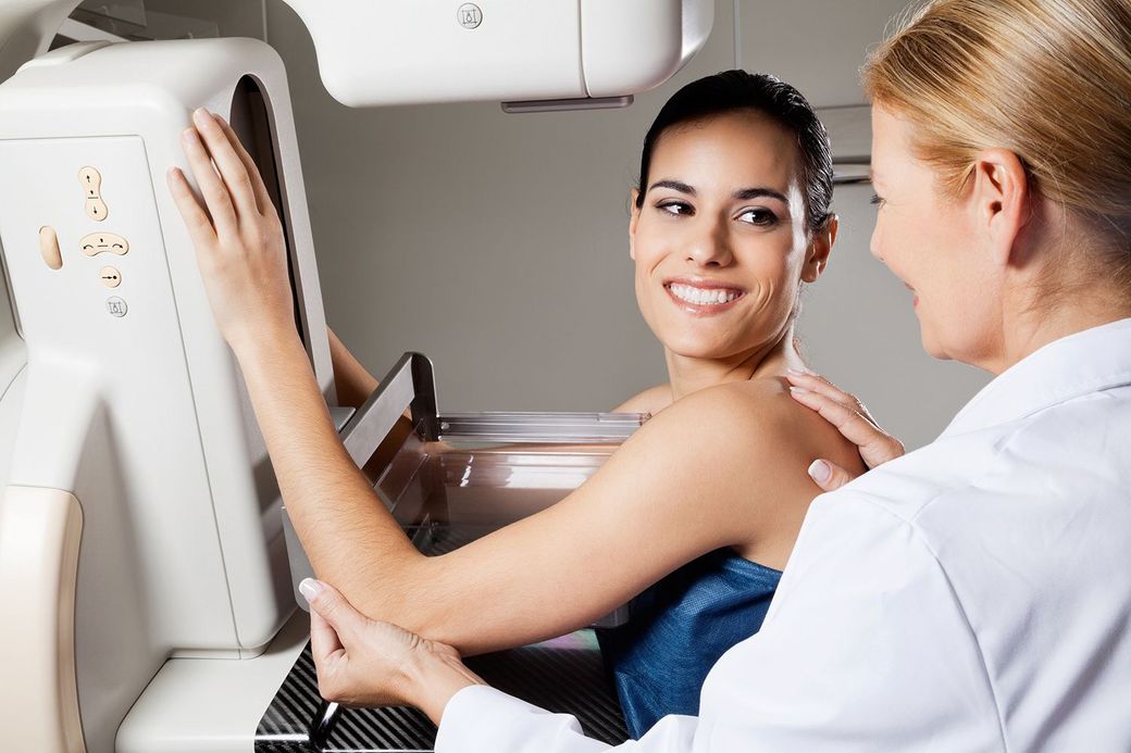 A woman is getting a mammogram from a doctor.