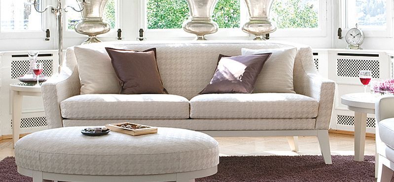 Ein Wohnzimmer mit einer weißen Couch und Ottomane