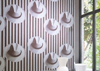 Eine gestreifte Wand mit einem Muster aus Cowboyhüten darauf.