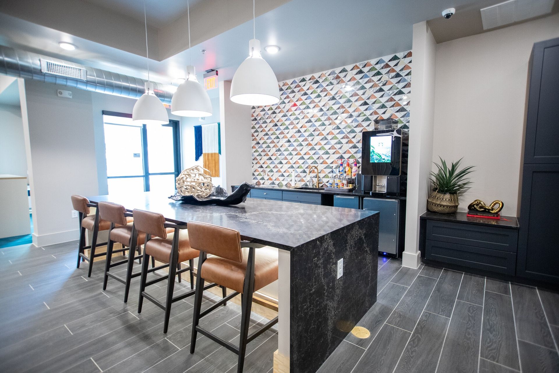 Modern communal kitchen/bar area with marble island, bar stools, and coffee station.