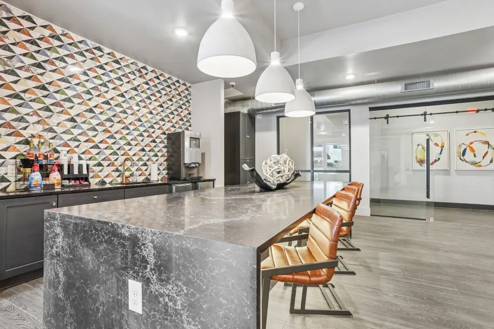 Modern kitchen with a patterned accent wall, bar seating, and pendant lights.