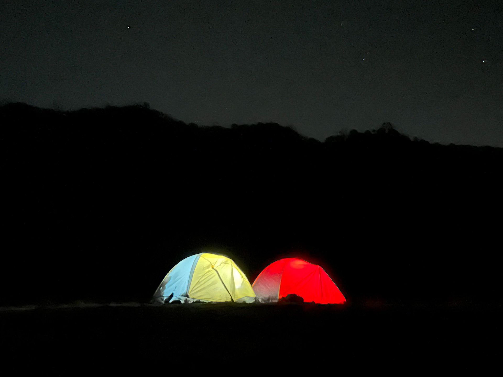 Two tents at night, lit from within