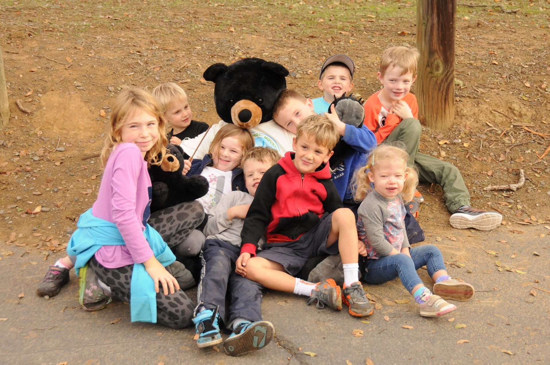 A group of children are posing for a picture with a teddy bear