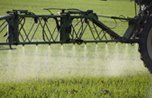 A tractor is spraying fertilizer on a lush green field.