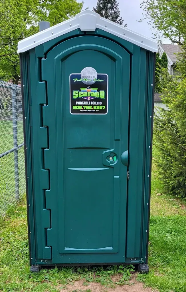 Green portable toilet with a white roof. Sign on the door reads