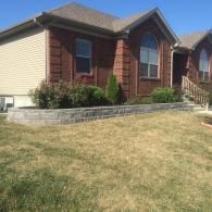 Suburban house with brick facade, beige siding, and a sloped front lawn