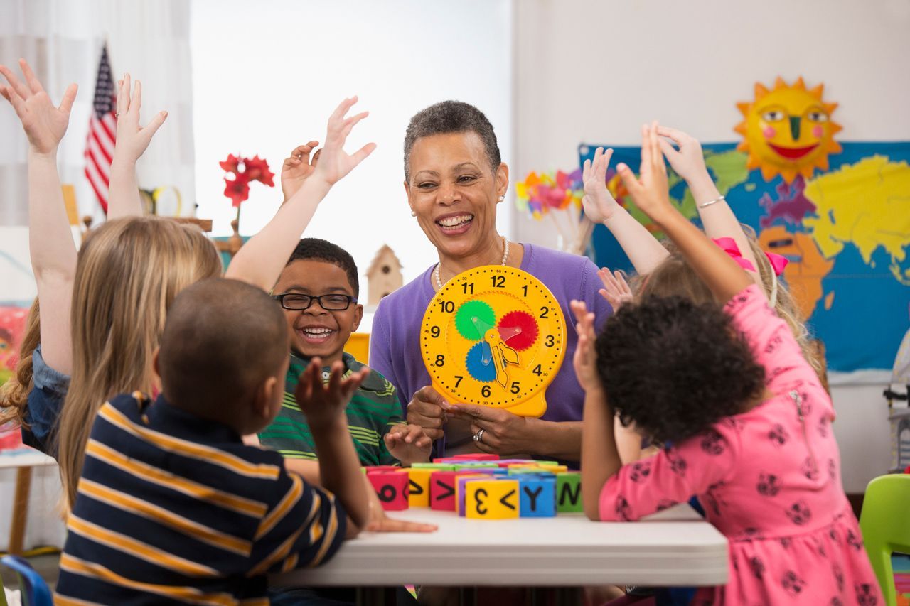 A teacher is teaching a group of children how to read a clock.
