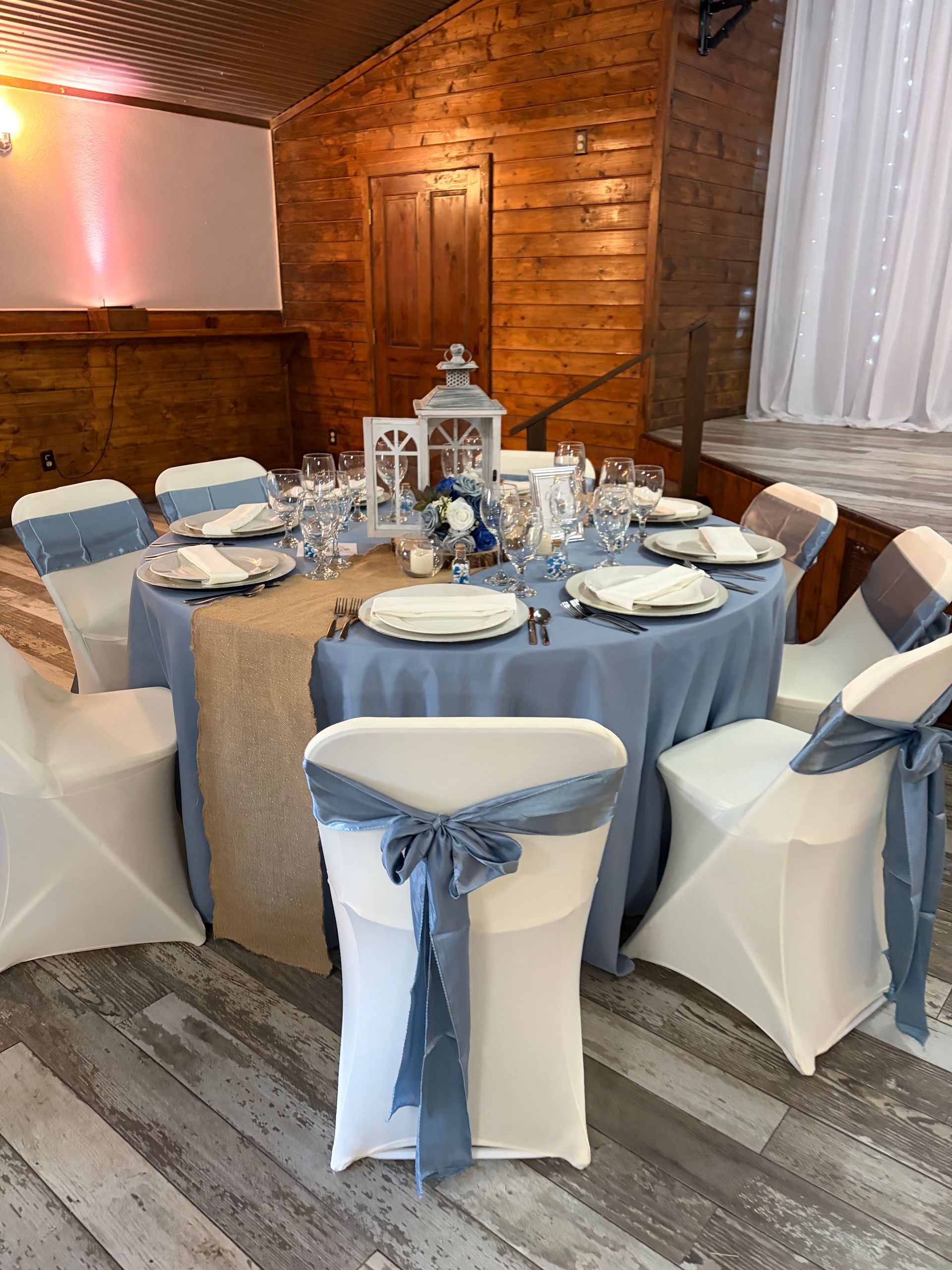 Outdoor wedding venue with rustic arch, benches, and stage, surrounded by trees.