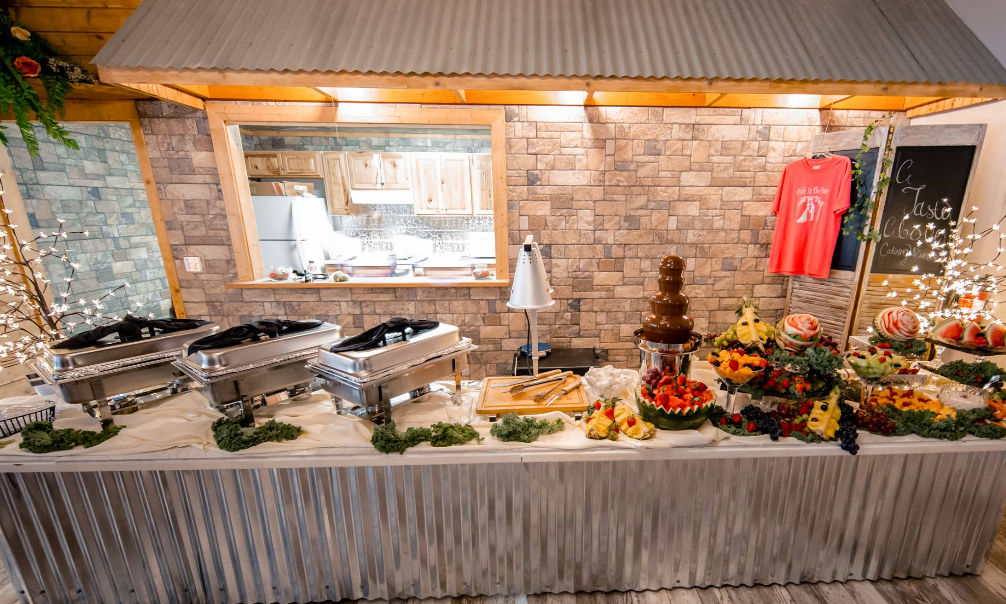 Bride and groom kissing, surrounded by guests blowing bubbles. String lights illuminate a barn.