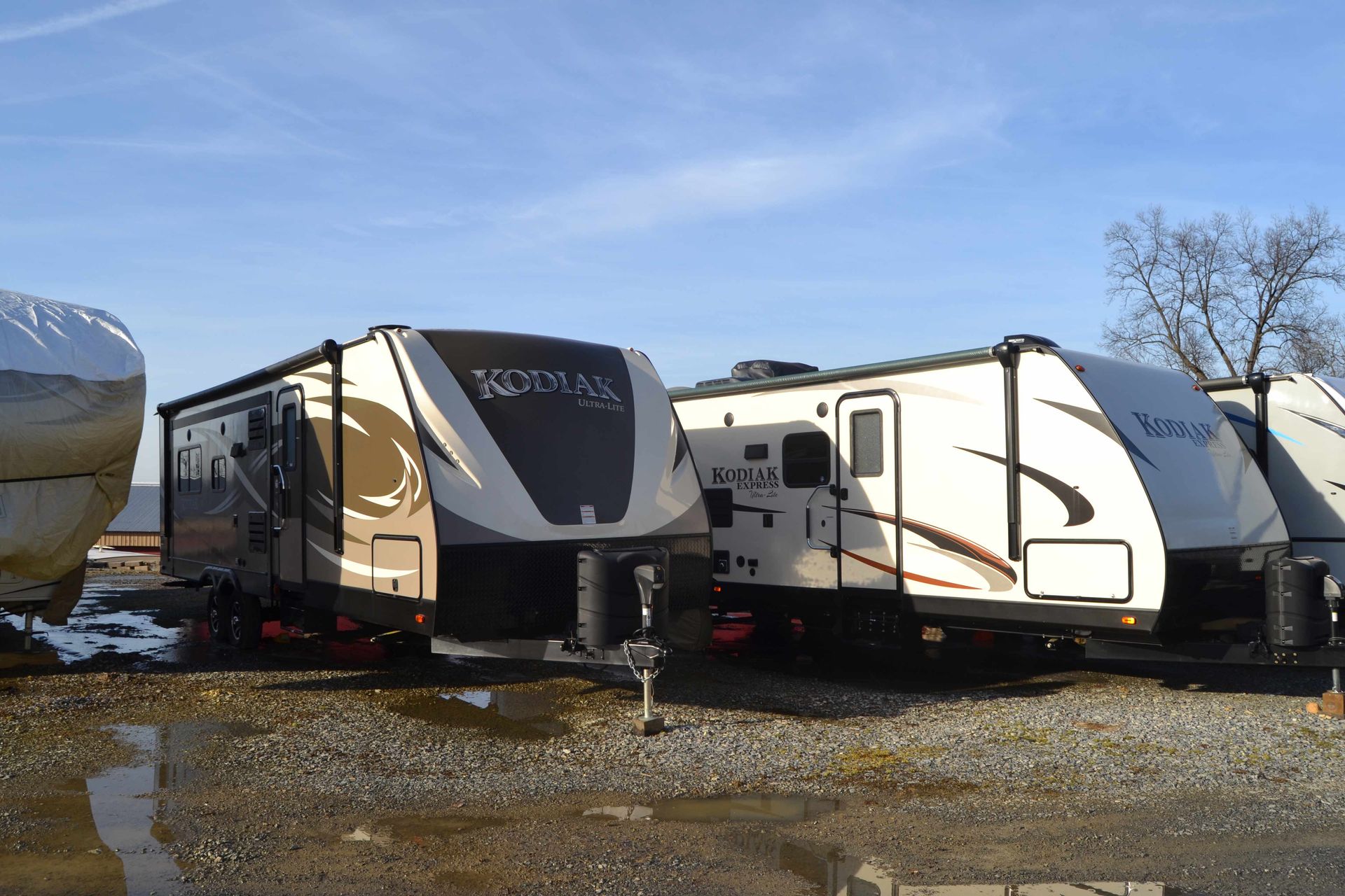 A row of travel trailers are parked in a parking lot.
