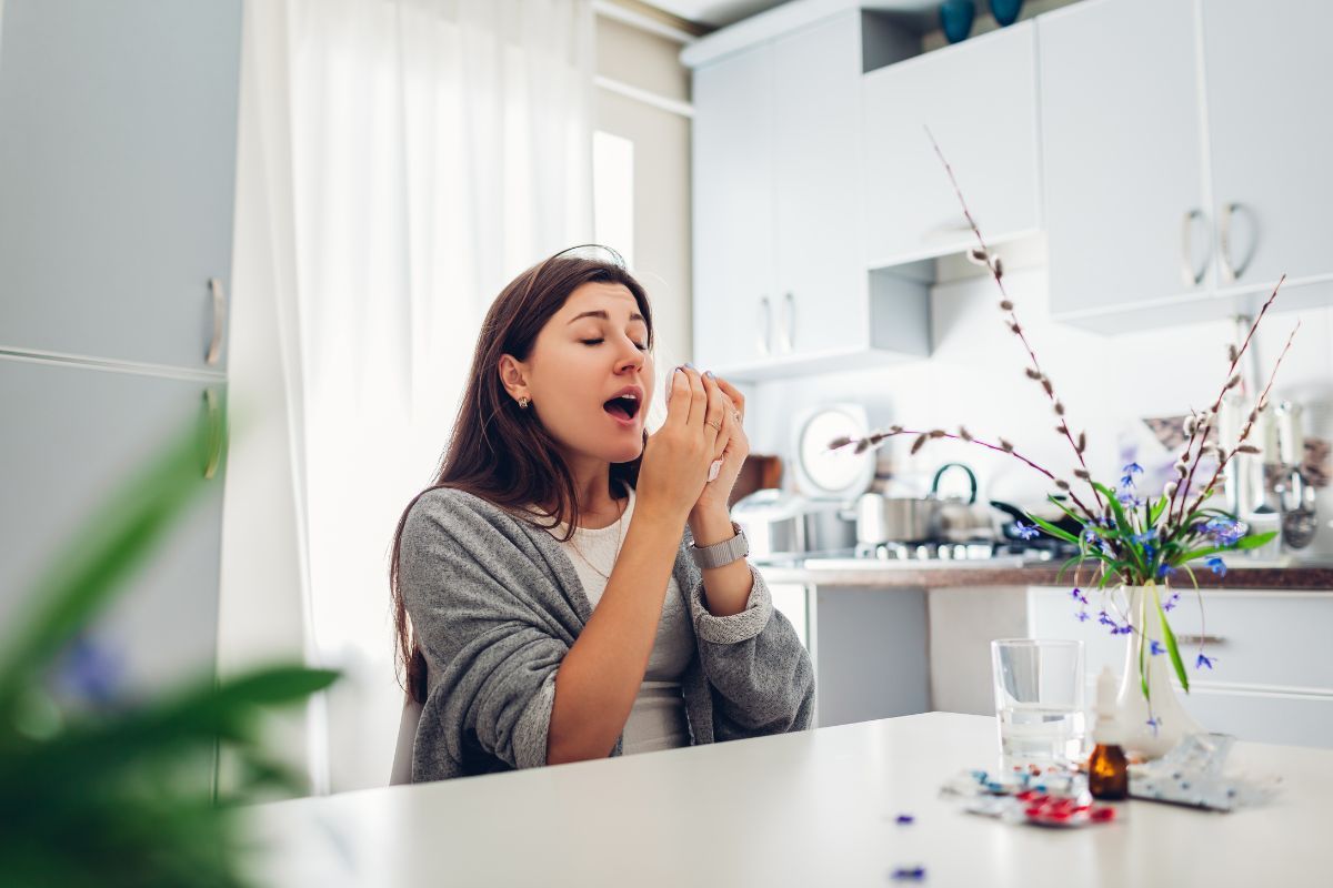 Women sneezing inside her kitchen due to allergies and poor air quality