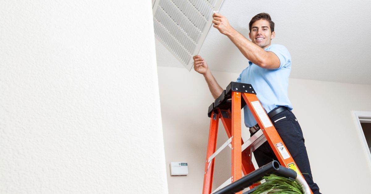 HVAC technician taking down vent for duct cleaning and repair