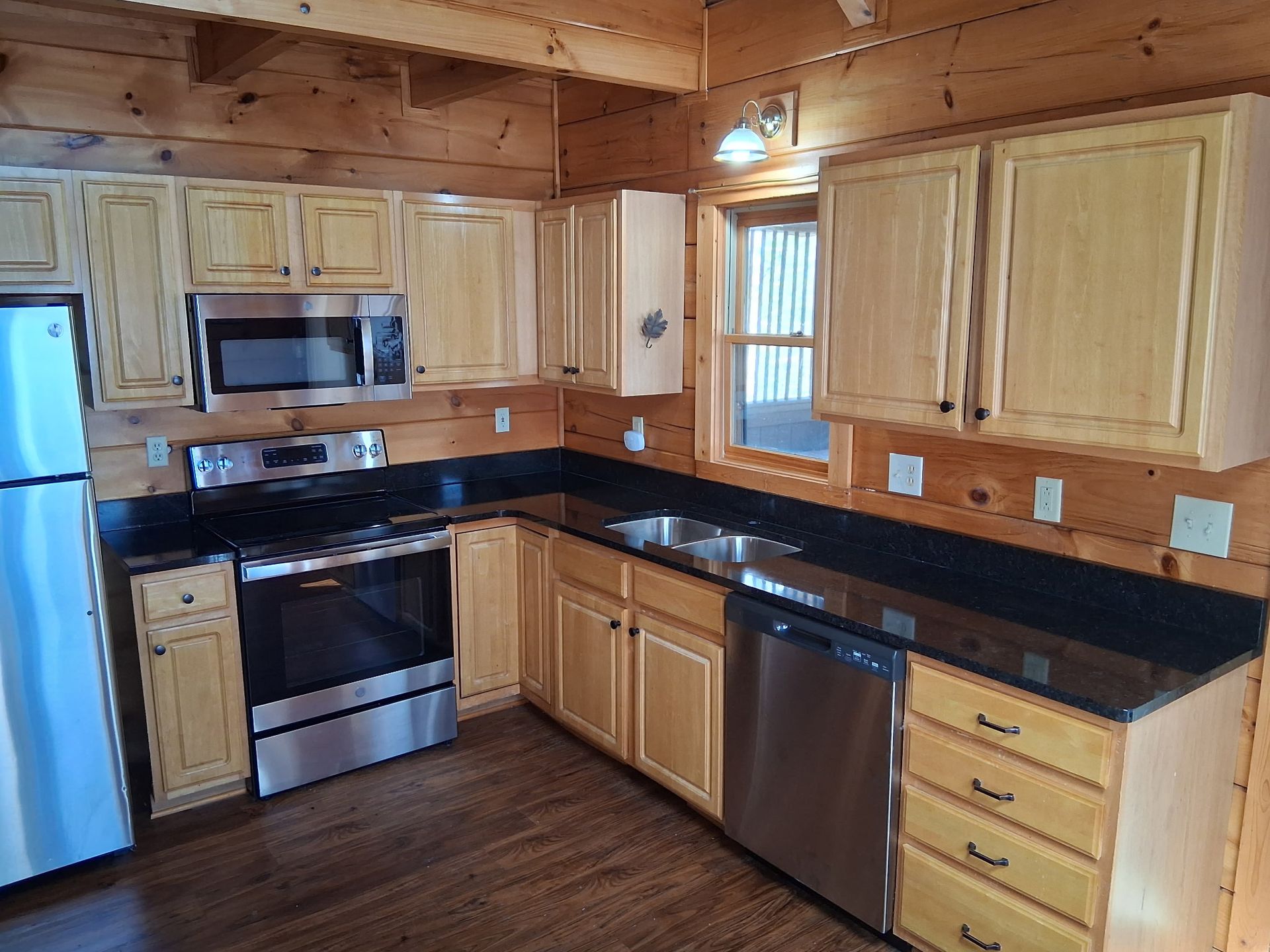 A kitchen in a log cabin with stainless steel appliances and wooden cabinets.