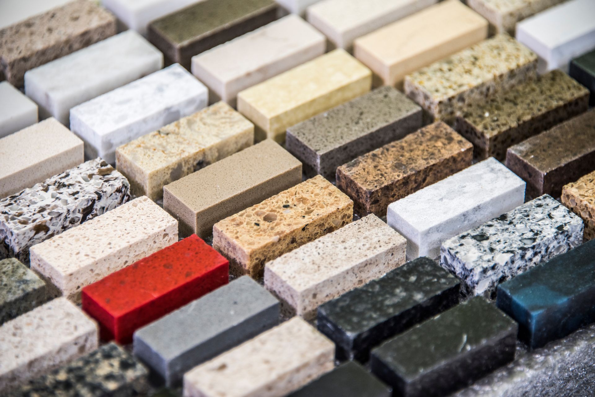 Assorted countertop material samples in various colors and textures arranged in neat rows.