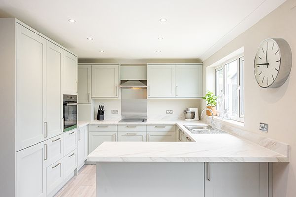 Modern white kitchen with marble kitchen countertops and built-in cabinets near window. Modern white kitchen with marble kitchen countertops and built-in cabinets near window.
