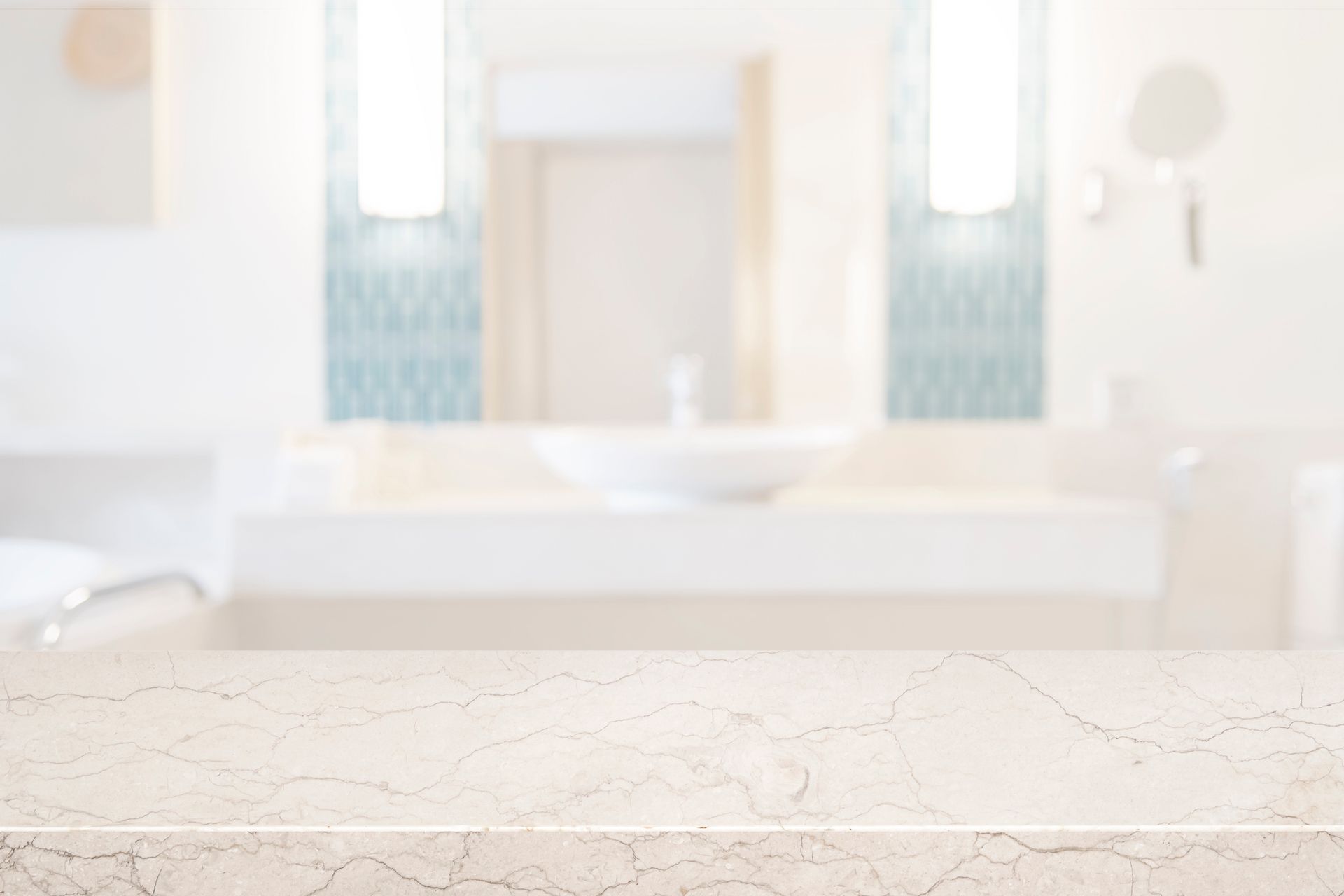 Marble countertop in a blurred bathroom setting with a sink, mirror, and lights.