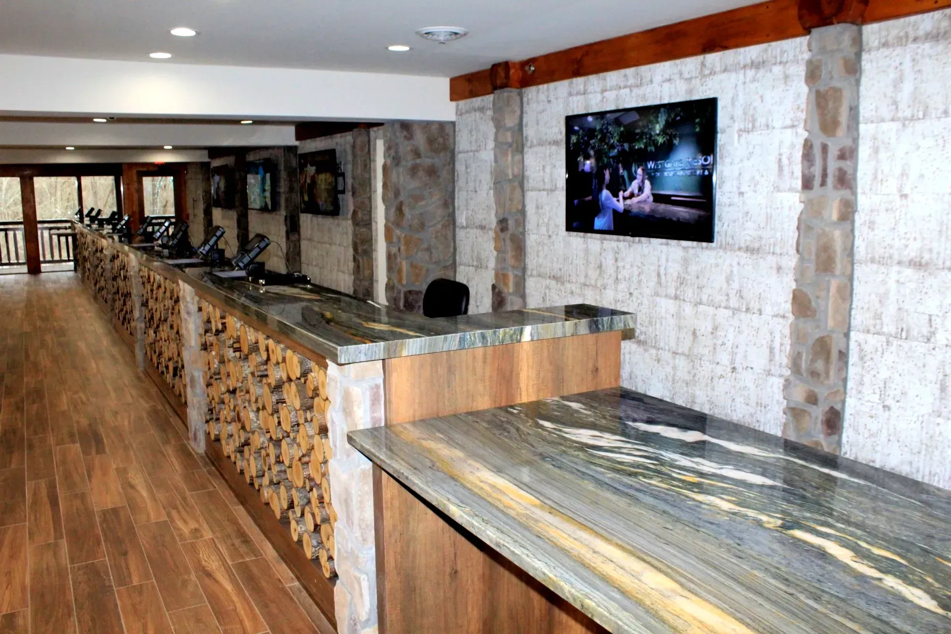 A long room with a long counter and a flat screen tv on the wall.