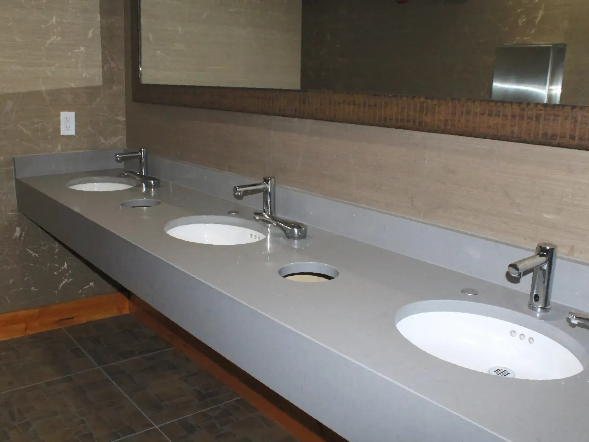 A bathroom with three sinks and a mirror