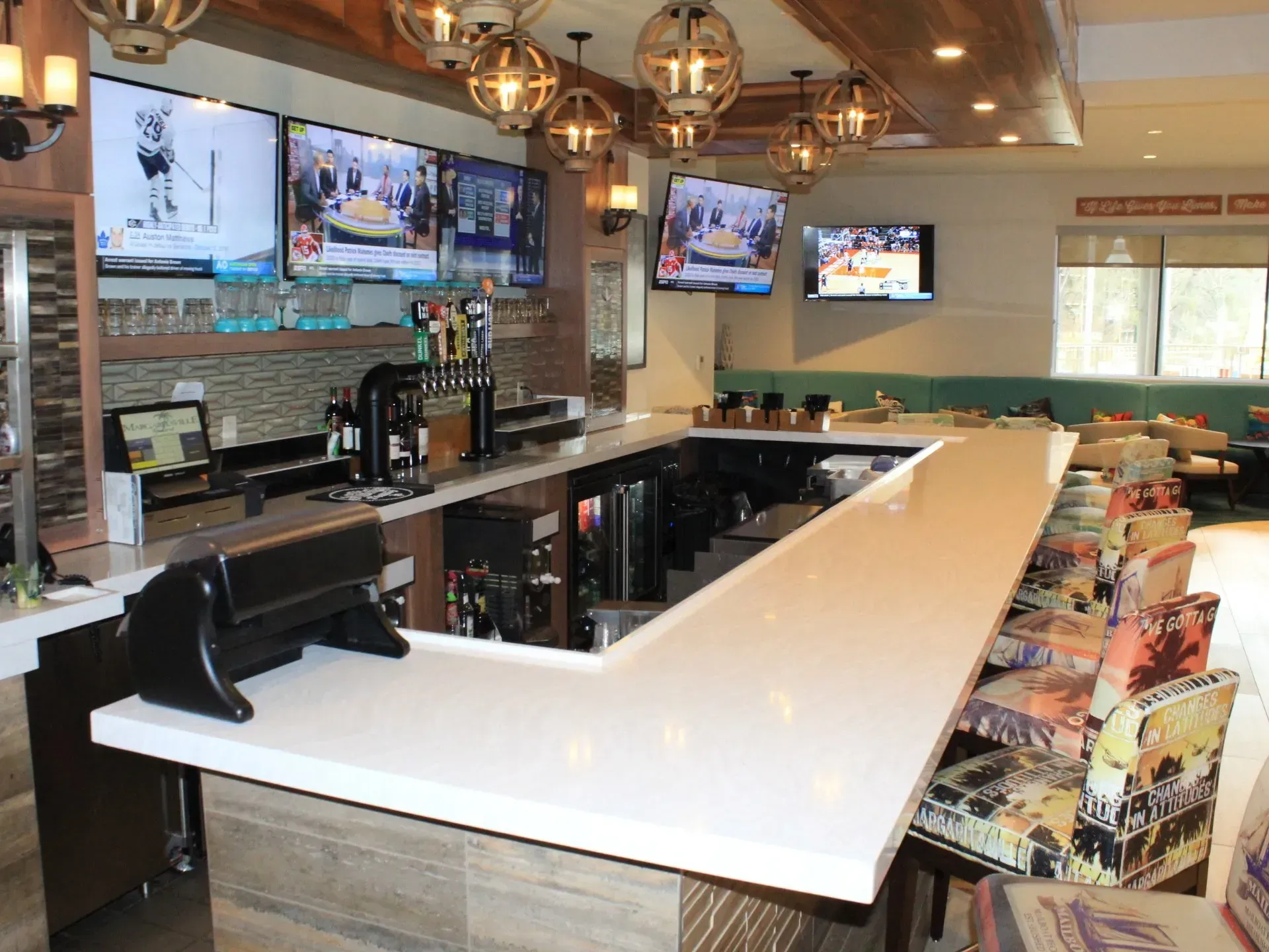 A long bar in a restaurant with a lot of televisions on the wall.