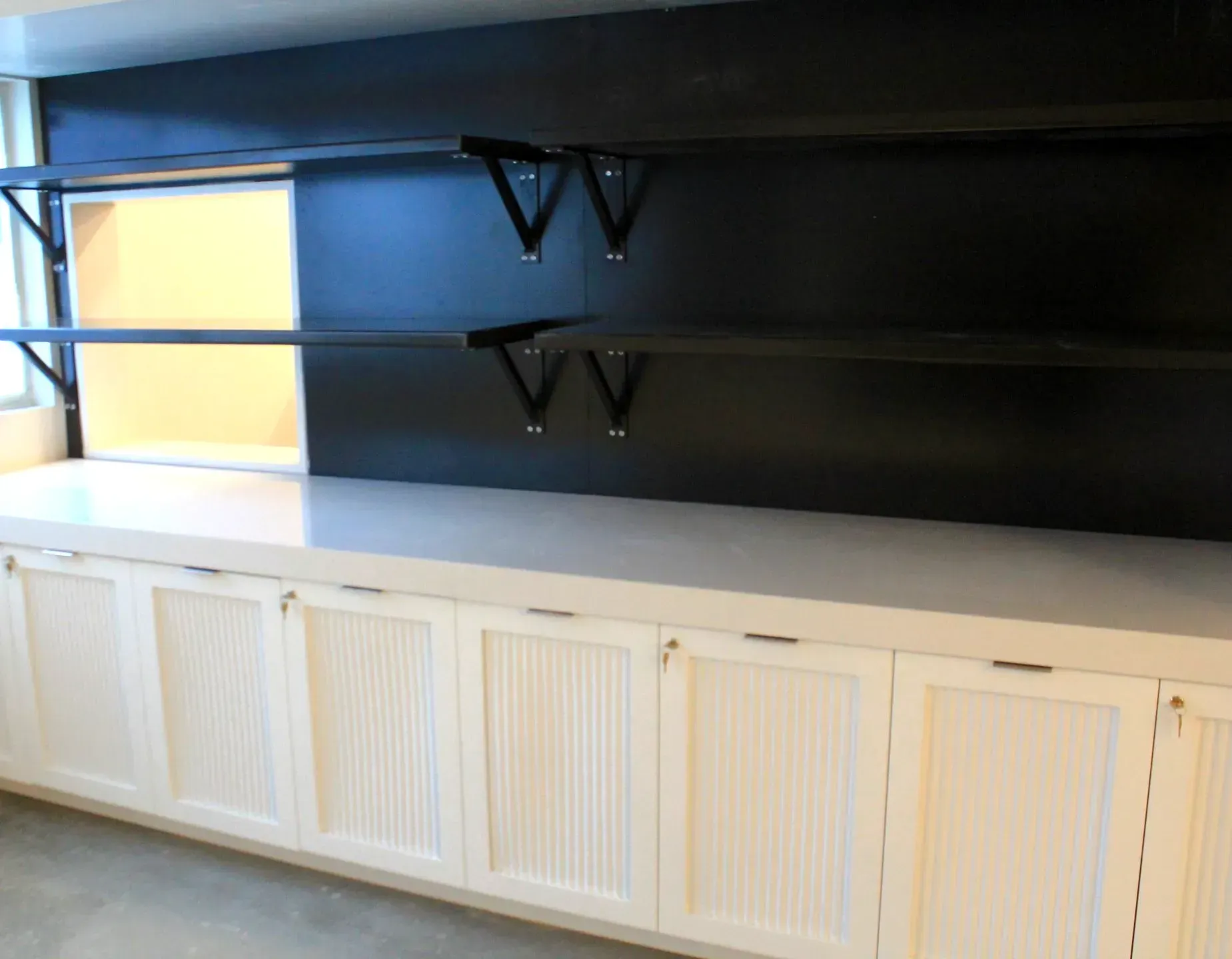 A kitchen with white cabinets and black shelves