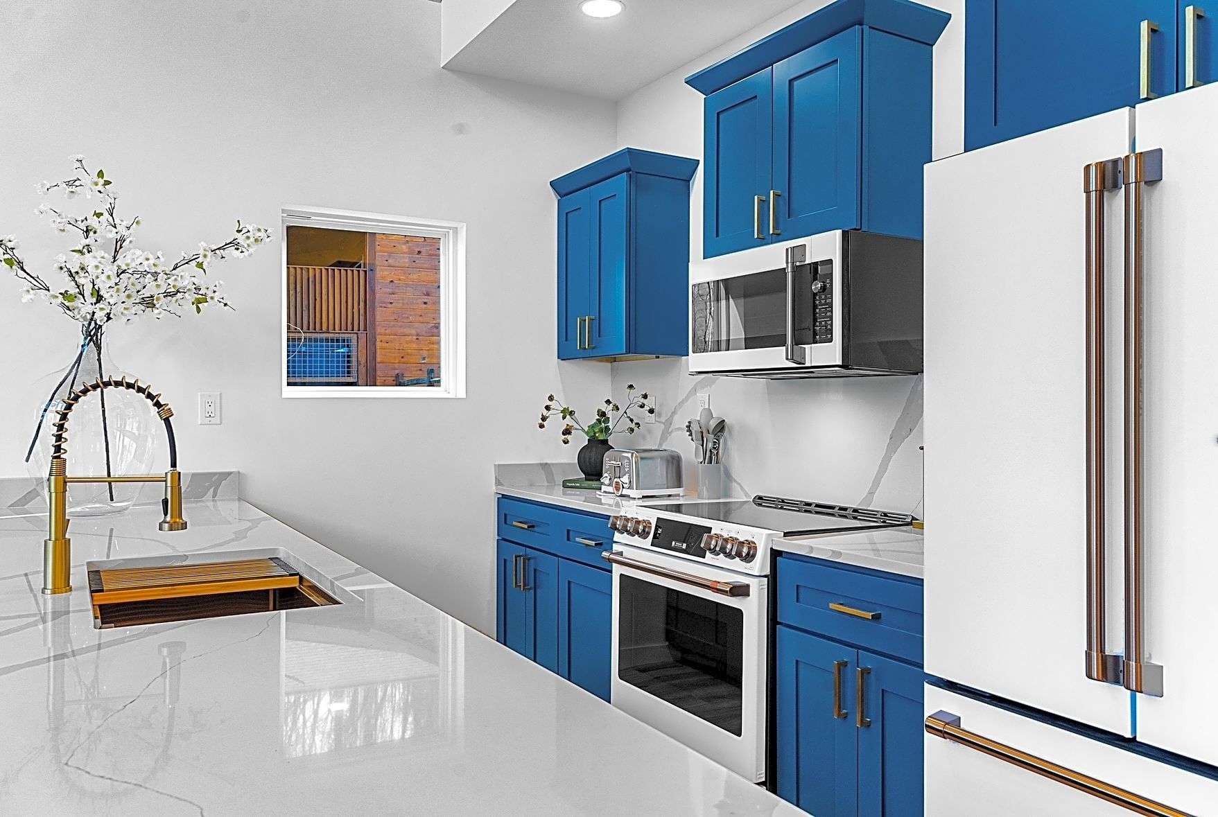 A kitchen with blue cabinets , stainless steel appliances , a sink , and a refrigerator.