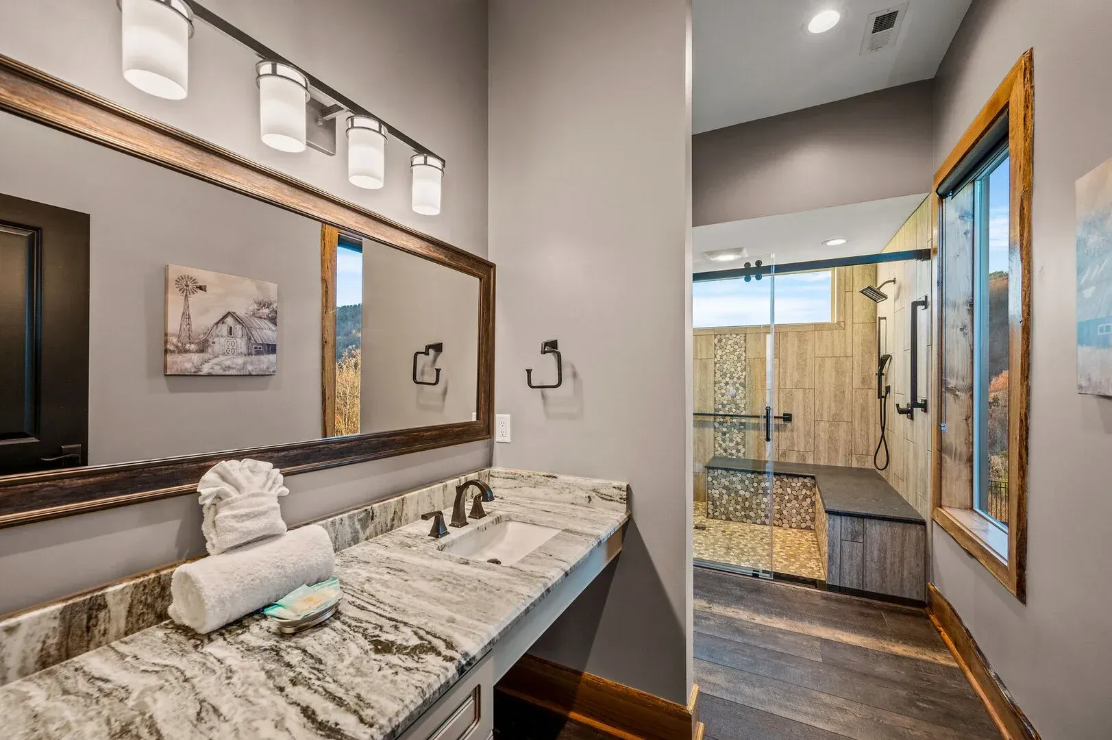 Bathroom with granite countertop, large mirror, and glass shower.