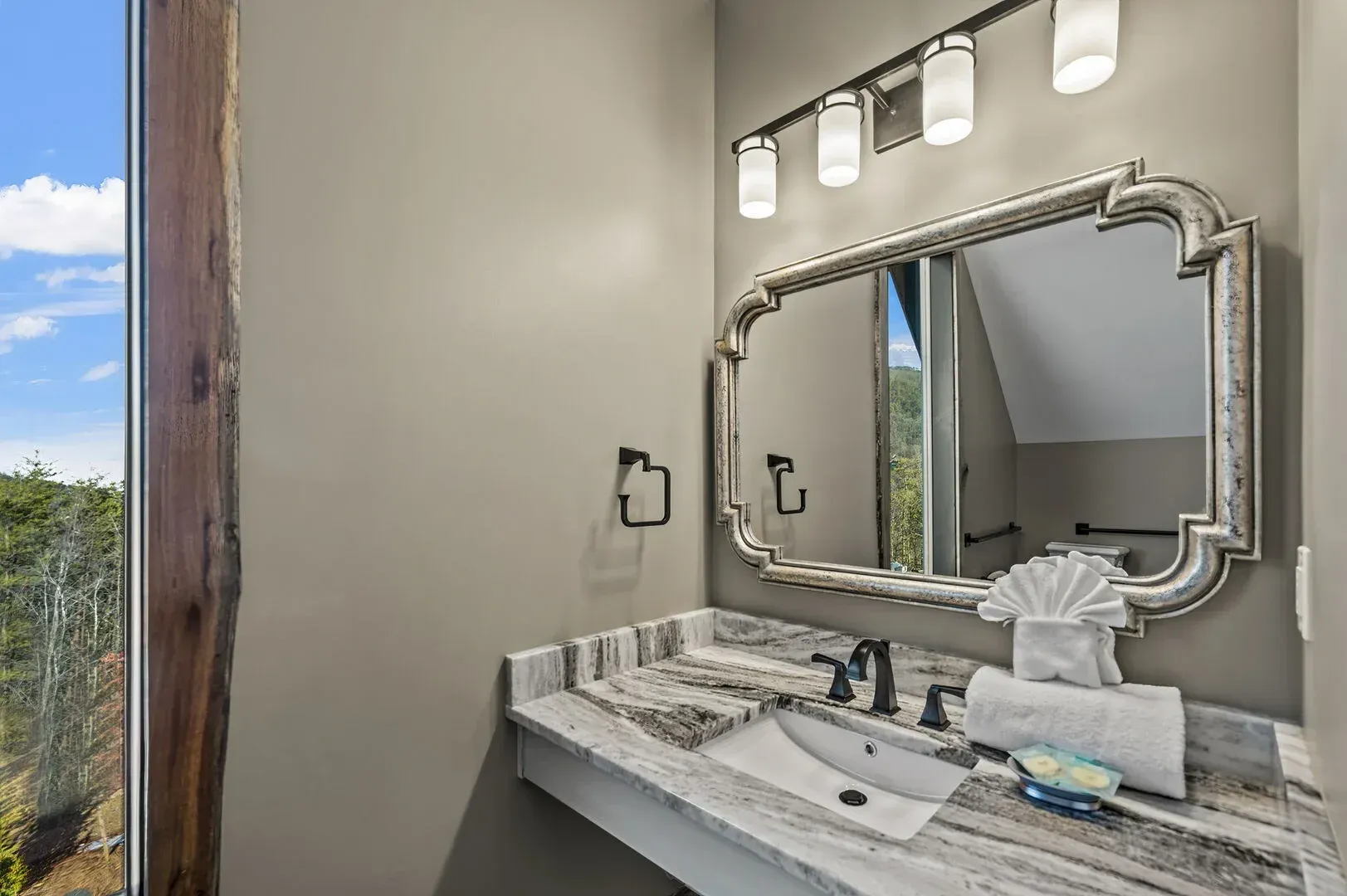 Bathroom with a decorative mirror, vanity with sink, and window with a view.