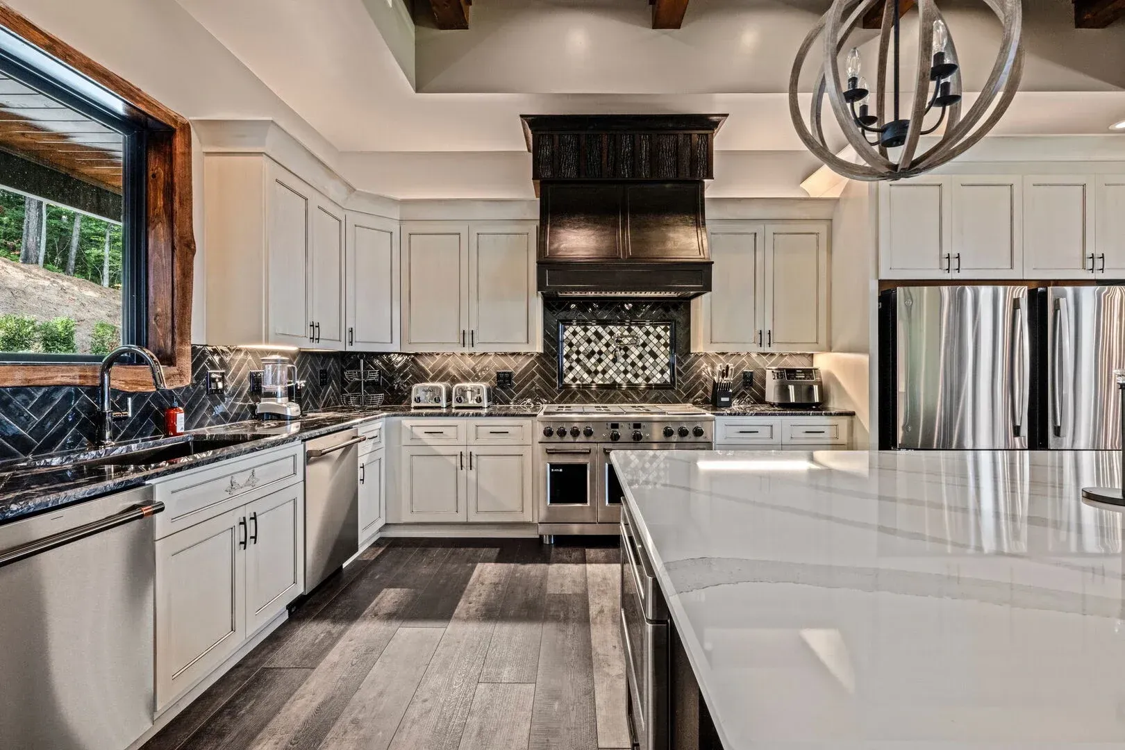 Modern kitchen with white cabinets, stainless steel appliances, and dark backsplash.