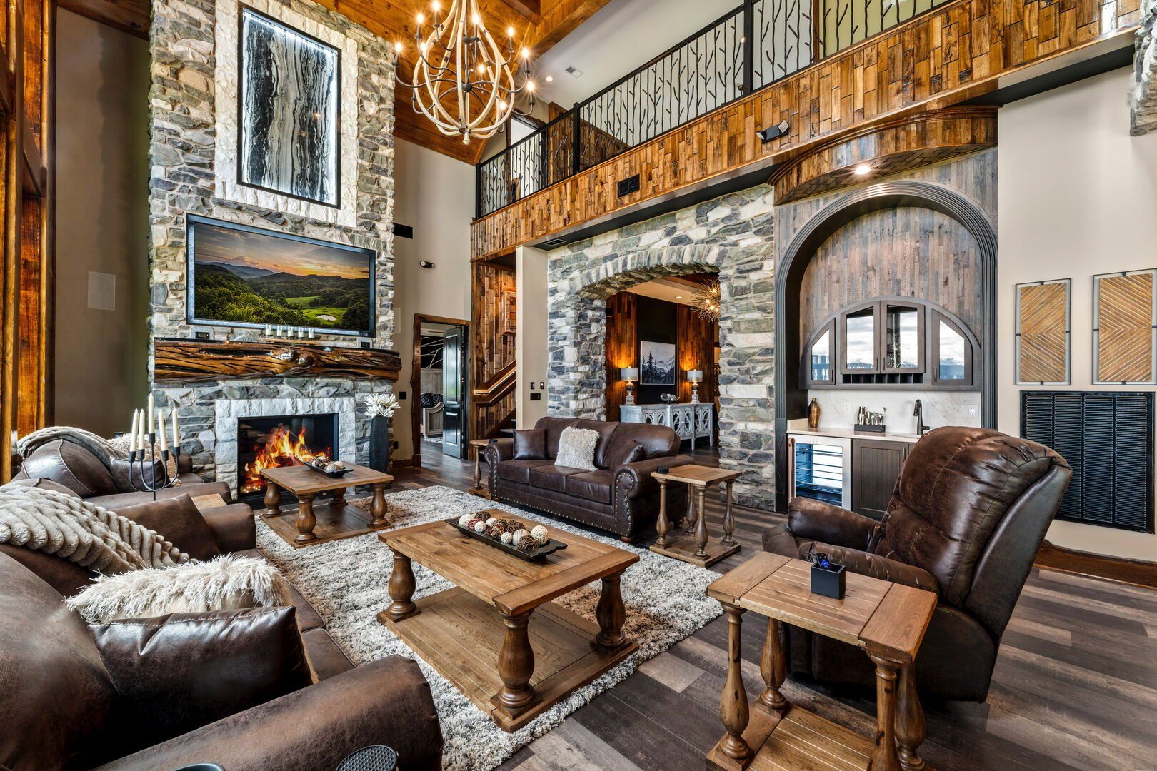 Spacious living room with stone walls, fireplace, leather furniture, and a bar area.