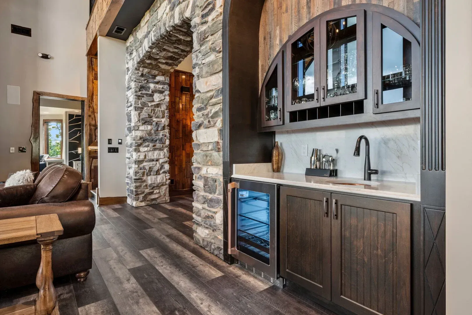 Interior with a built-in bar area featuring cabinetry, a sink, wine cooler, and arched glass-door upper cabinets.