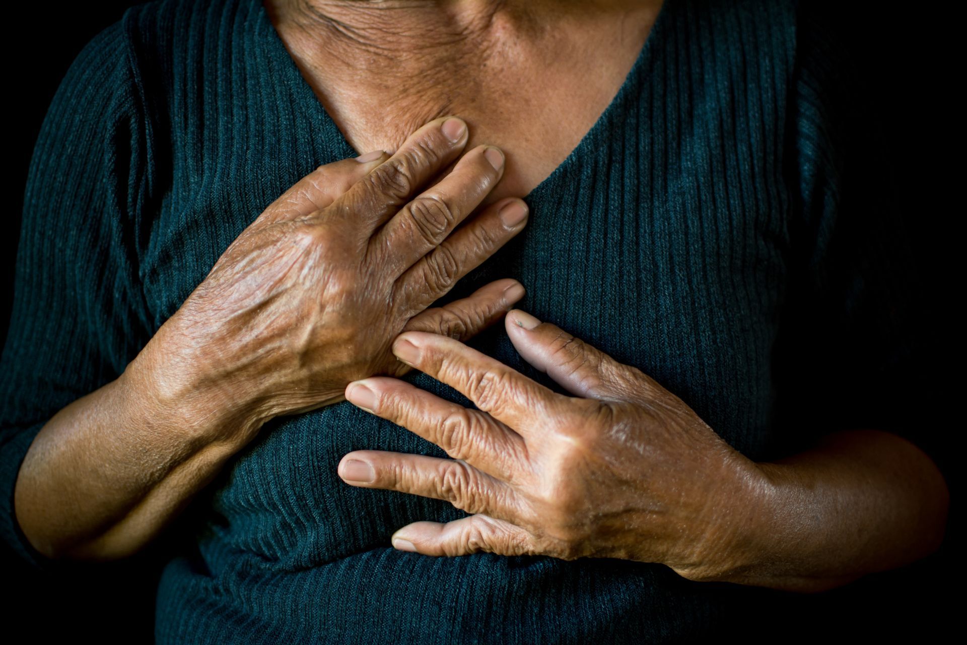 closeup of elderly woman holding hands over her heart