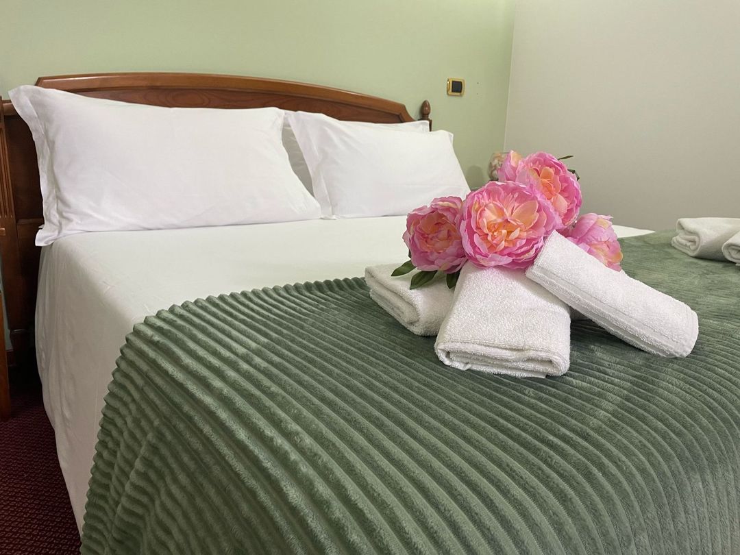 Un letto con asciugamani e fiori in una stanza d'albergo.