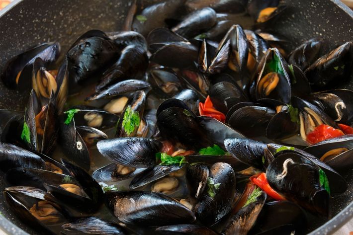 Una padella piena di cozze e verdure su un tavolo.