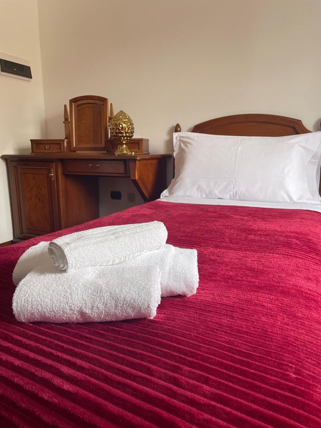Un letto con una coperta rossa e lenzuola bianche