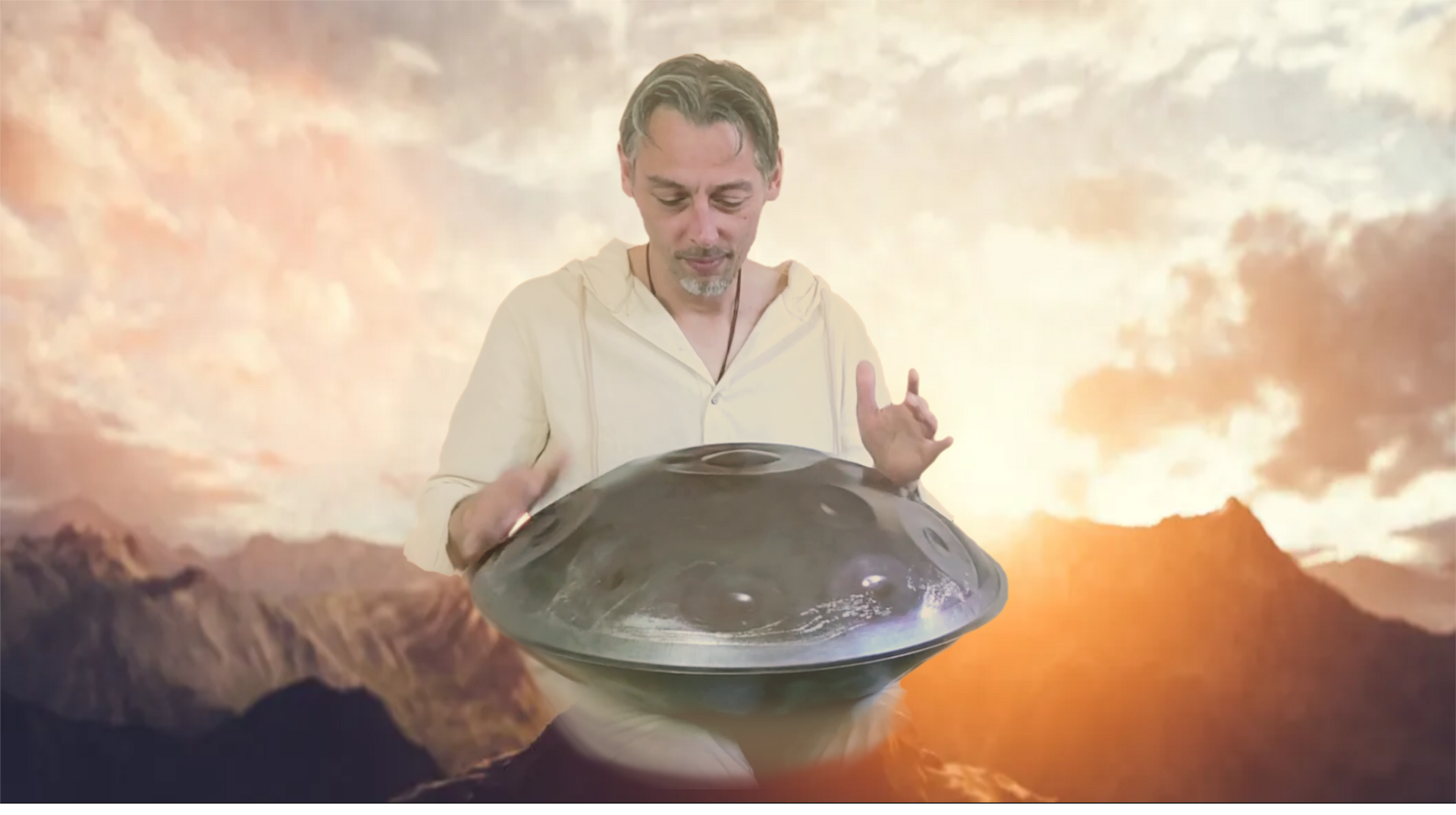 Man die een handpan bespeelt met een berglandschap op de achtergrond.