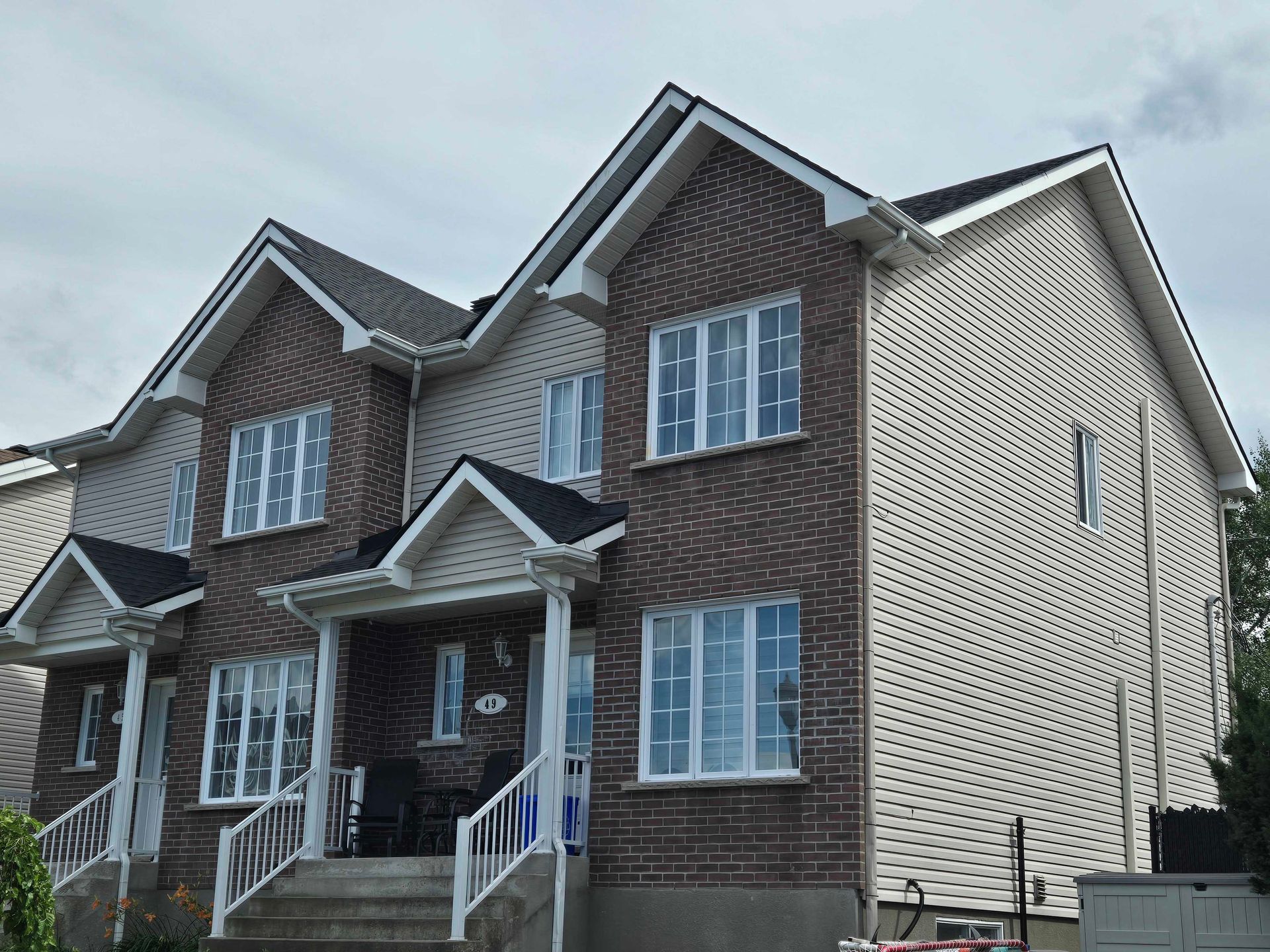 Maisons de ville en briques de deux étages, avec des façades en briques claires et foncées, sous un ciel nuageux.