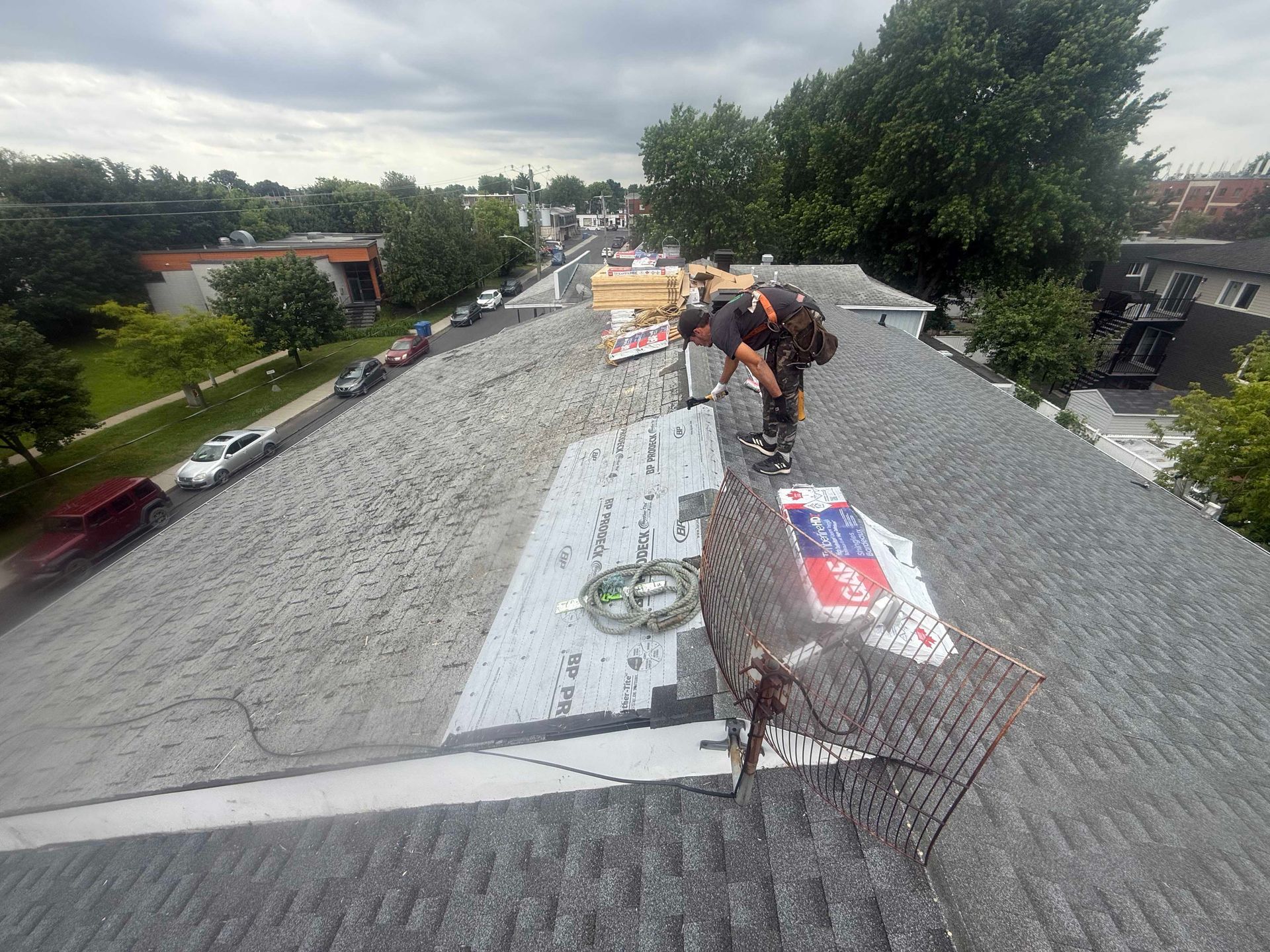 Des couvreurs travaillent sur un toit résidentiel, en bardeaux d'asphalte, par une belle journée.
