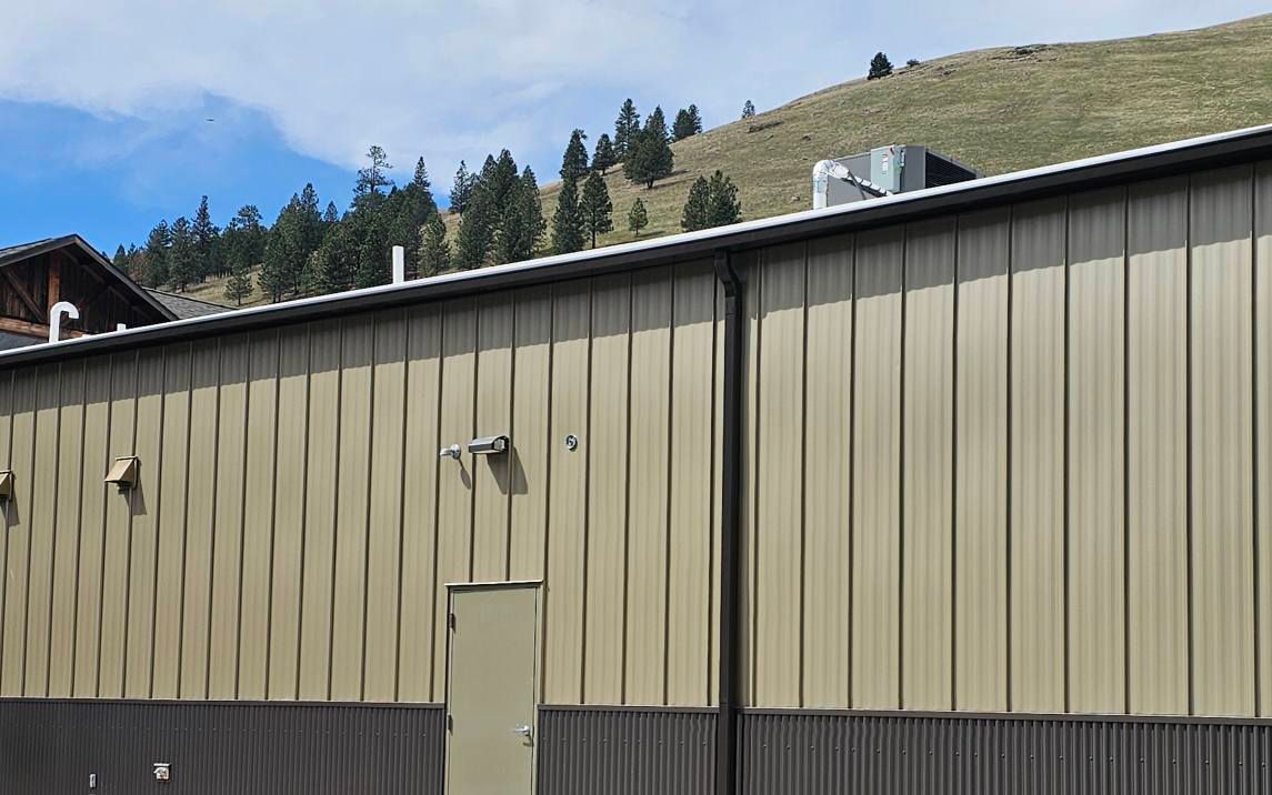 A large metal building with a door and a mountain in the background.