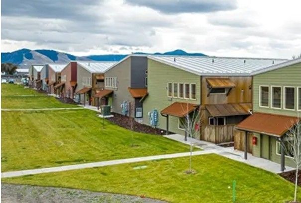 A row of houses sitting next to each other on top of a lush green field.
