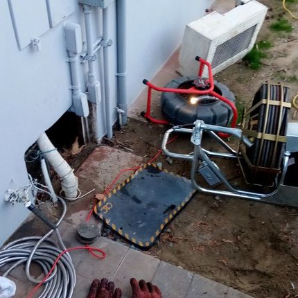 Plumber's equipment next to a wall. Includes a camera, drain snake, and hole in the wall.