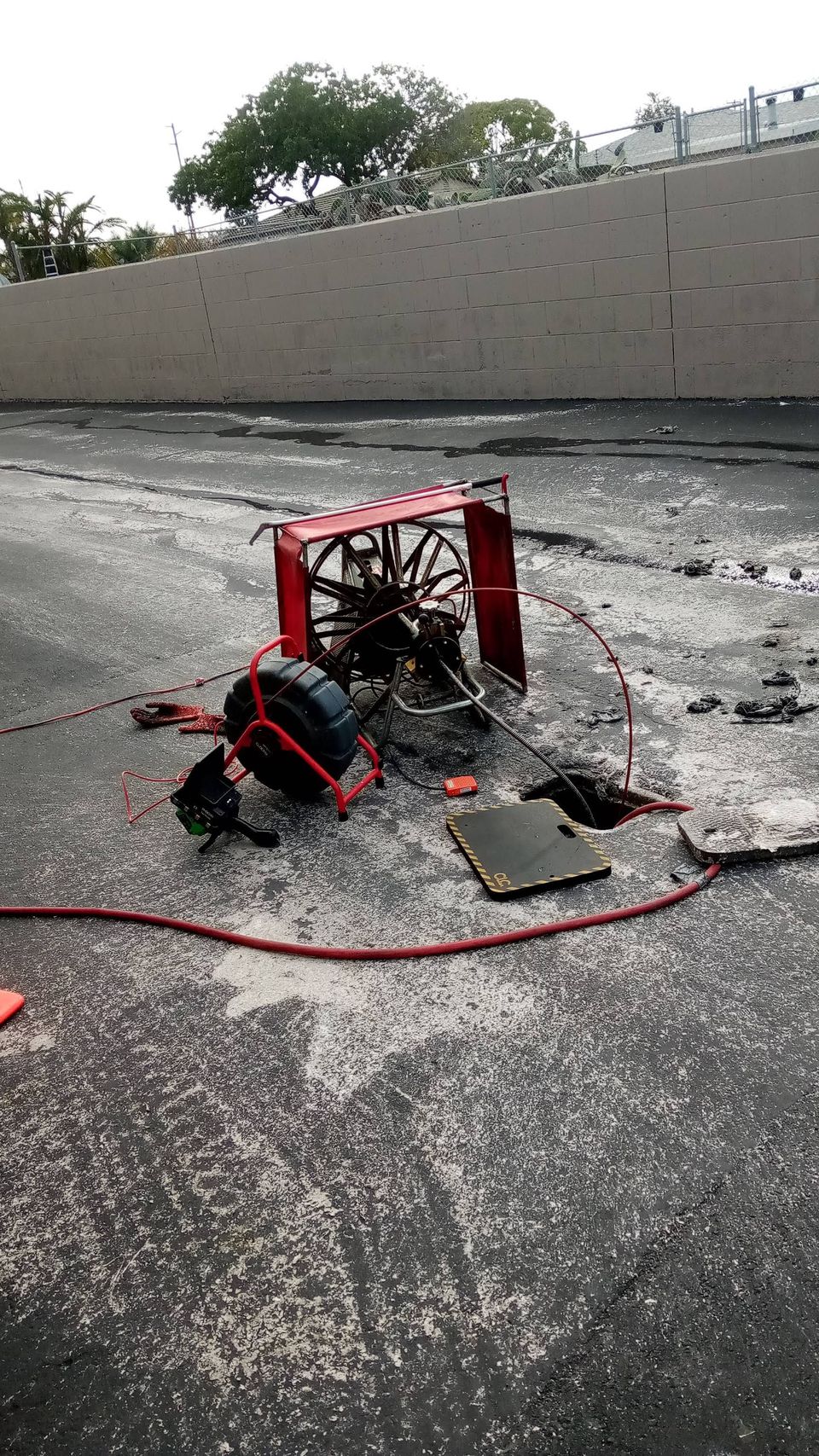 A damaged red fire hose reel lies on a dark, cracked asphalt surface.