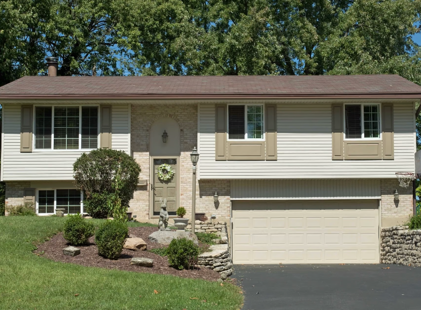 A white house with a brown roof and a tan garage door