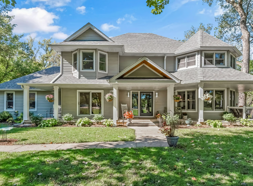 A large house with a lot of windows is sitting on top of a lush green lawn.