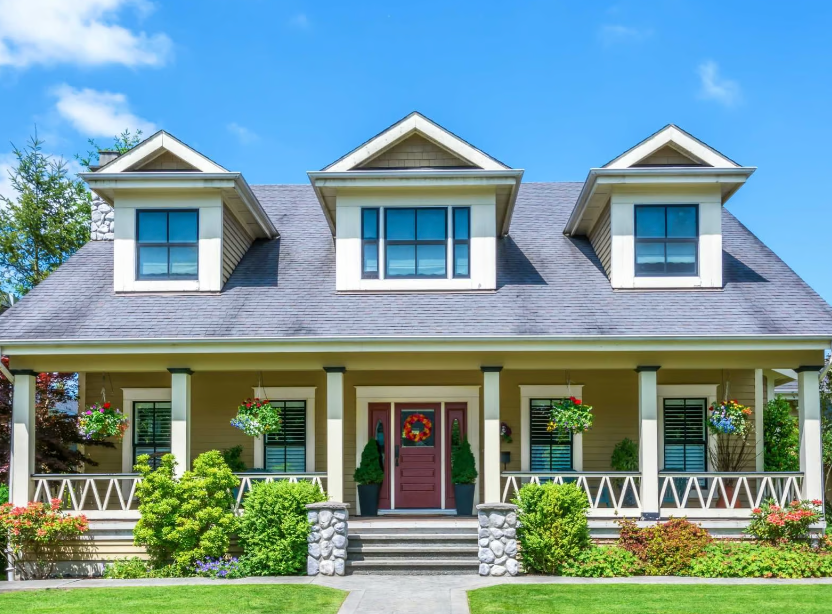 A large house with a large porch and a blue sky in the background.