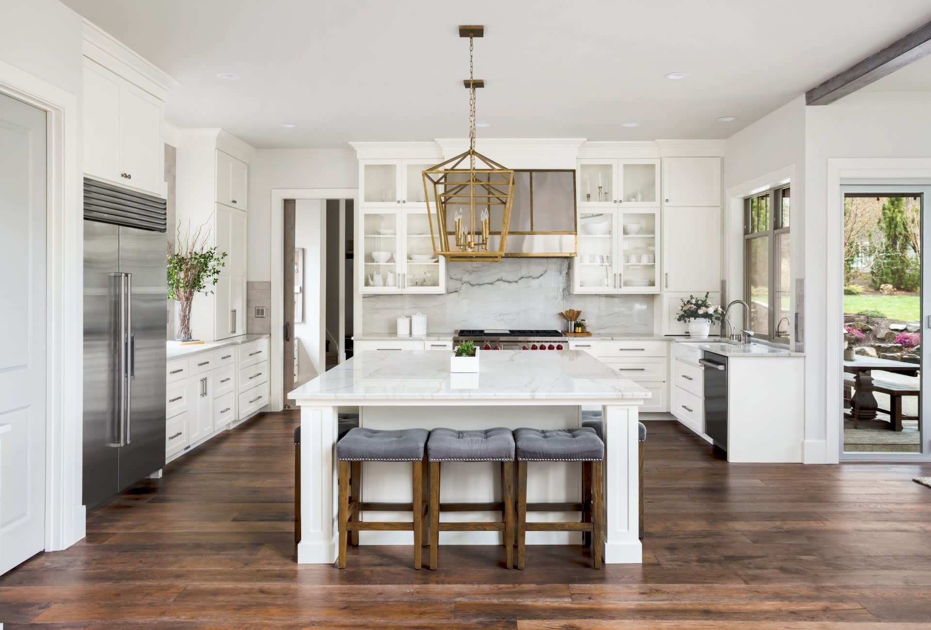 A kitchen with white cabinets , stainless steel appliances , and a large island.