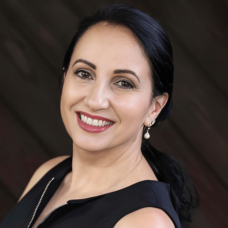 A woman wearing a black dress and earrings smiles for the camera